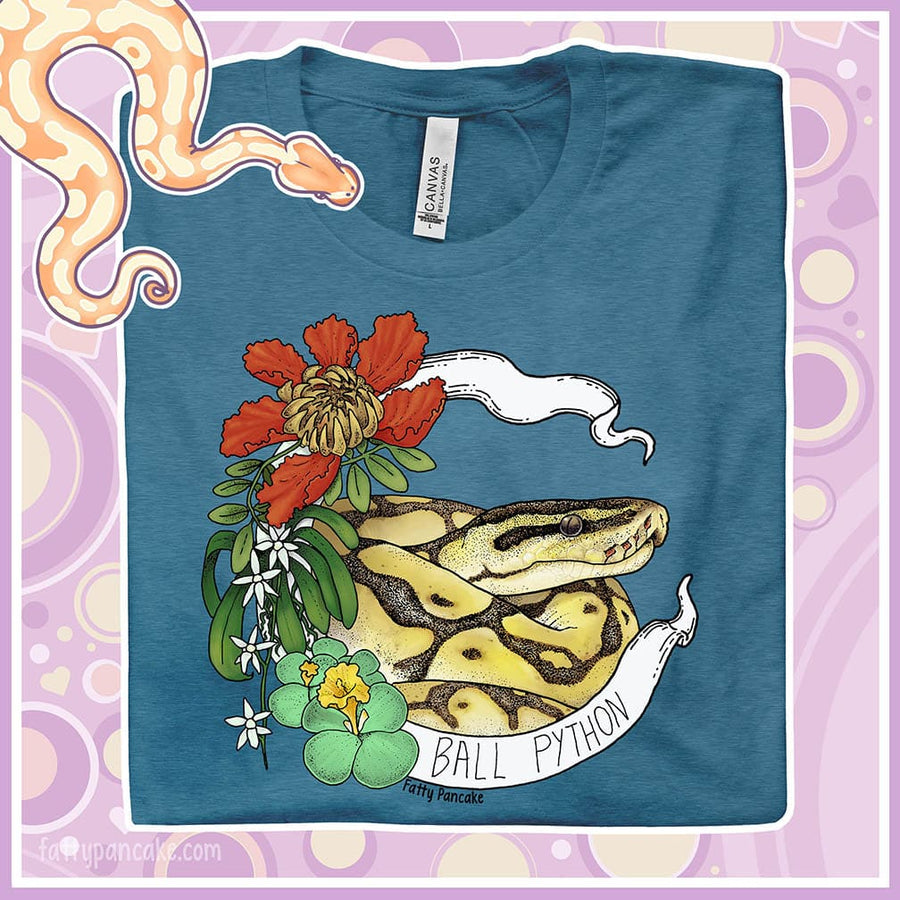 Image shows a heather teal colored crew neck tee with a ball python coiled up in a white banner with the snake species on it. Red, white, and green flowers and plants adorn the left side of the graphic.