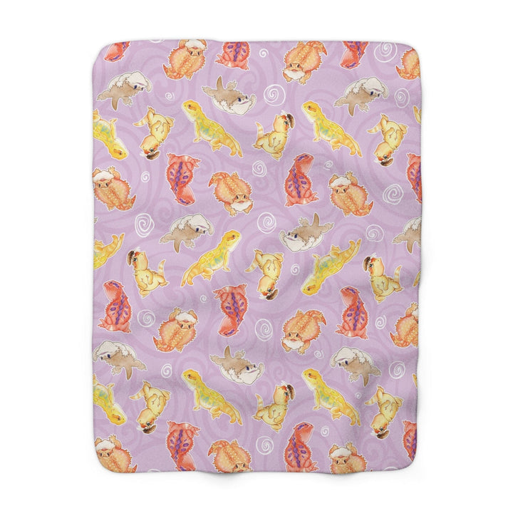Purple blanket with colorful bearded dragon pattern on a white background.