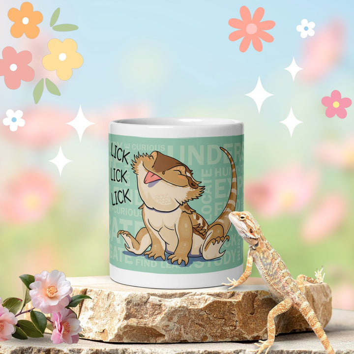 A white ceramic mug with a cartoon bearded dragon illustration and the word &