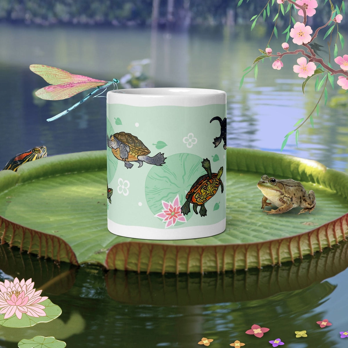 A white ceramic mug featuring a light green background with a repeating pattern of small turtles, pink lotus flowers, and green lily pads. The design includes stylized white floral accents scattered across the surface of the mug.