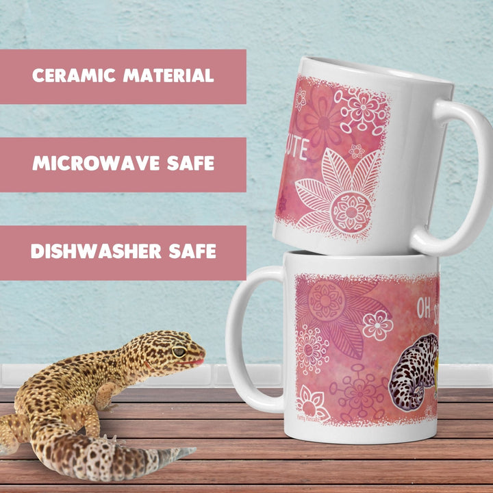Two stacked white ceramic mugs with pink floral and leopard-print designs, shown on a wooden surface against a light blue wall. Text on the left reads &