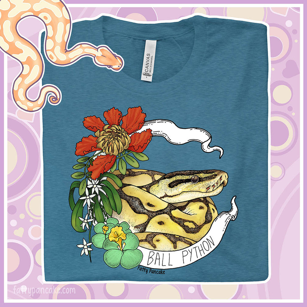 Image shows a heather teal colored crew neck tee with a ball python coiled up in a white banner with the snake species on it. Red, white, and green flowers and plants adorn the left side of the graphic.