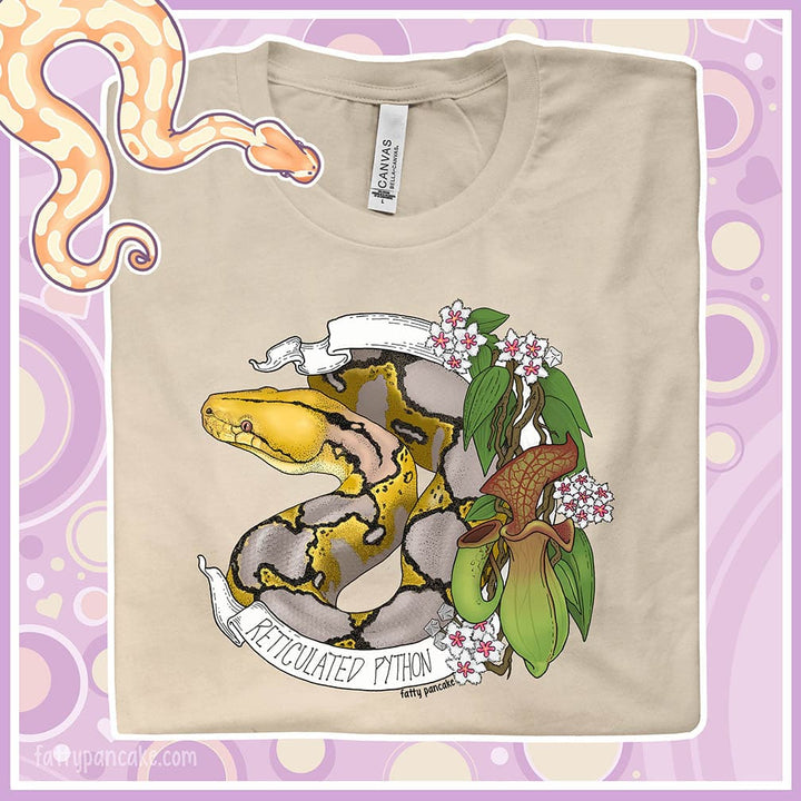 Image showing a close up of a tee shirt graphic. The tan colored crew neck tee sports a normal phase reticulated python framed by pitcher plants, white flowers, and a white banner with the text, "Reticulated Python" on it.