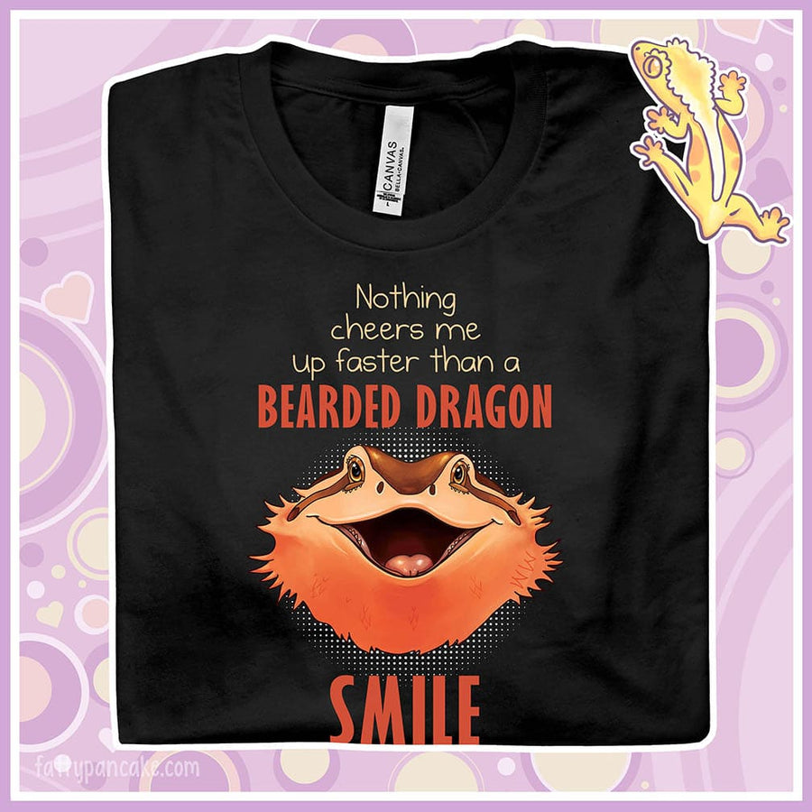 A folded black crew neck tee showing a smiling bearded dragon with the text Nothing cheers me up faster than a bearded dragon smile.