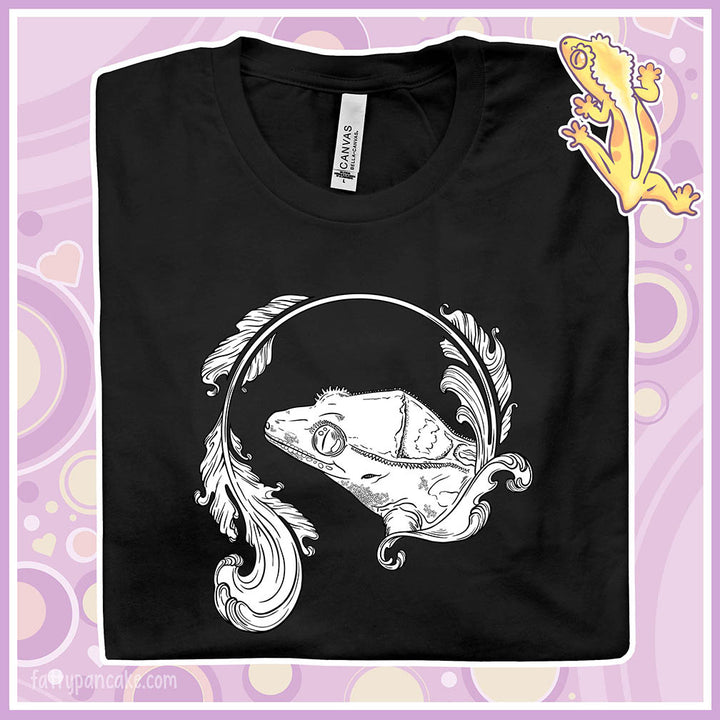 A folded black crew neck tee with a black and white graphic of a crested gecko done in delicate line work and elegant flourish designs.