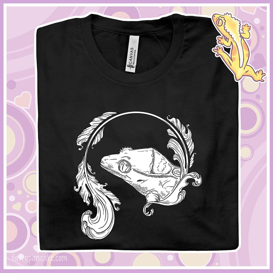 A folded black crew neck tee with a black and white graphic of a crested gecko done in delicate line work and elegant flourish designs.