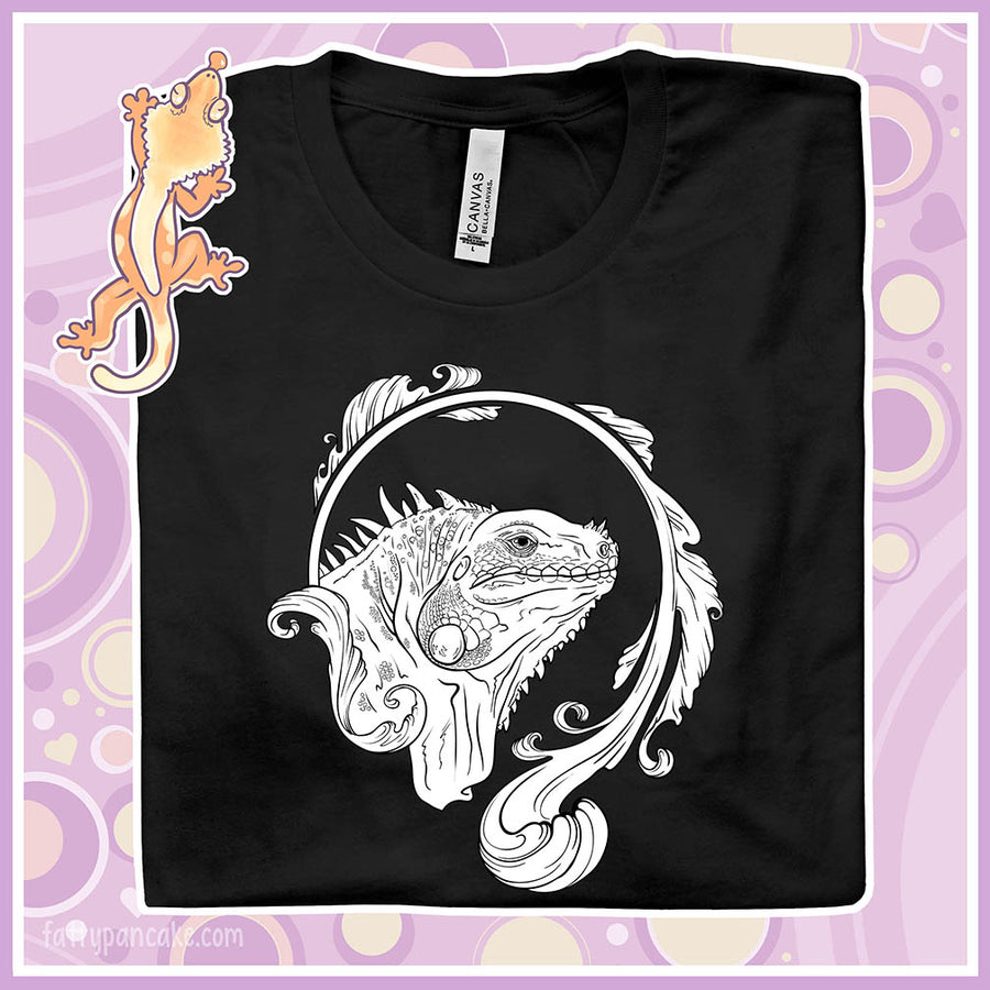 Folded black crew neck tee with a black and white line art graphic of an iguana with an elegant flourish design swirling around the animal.