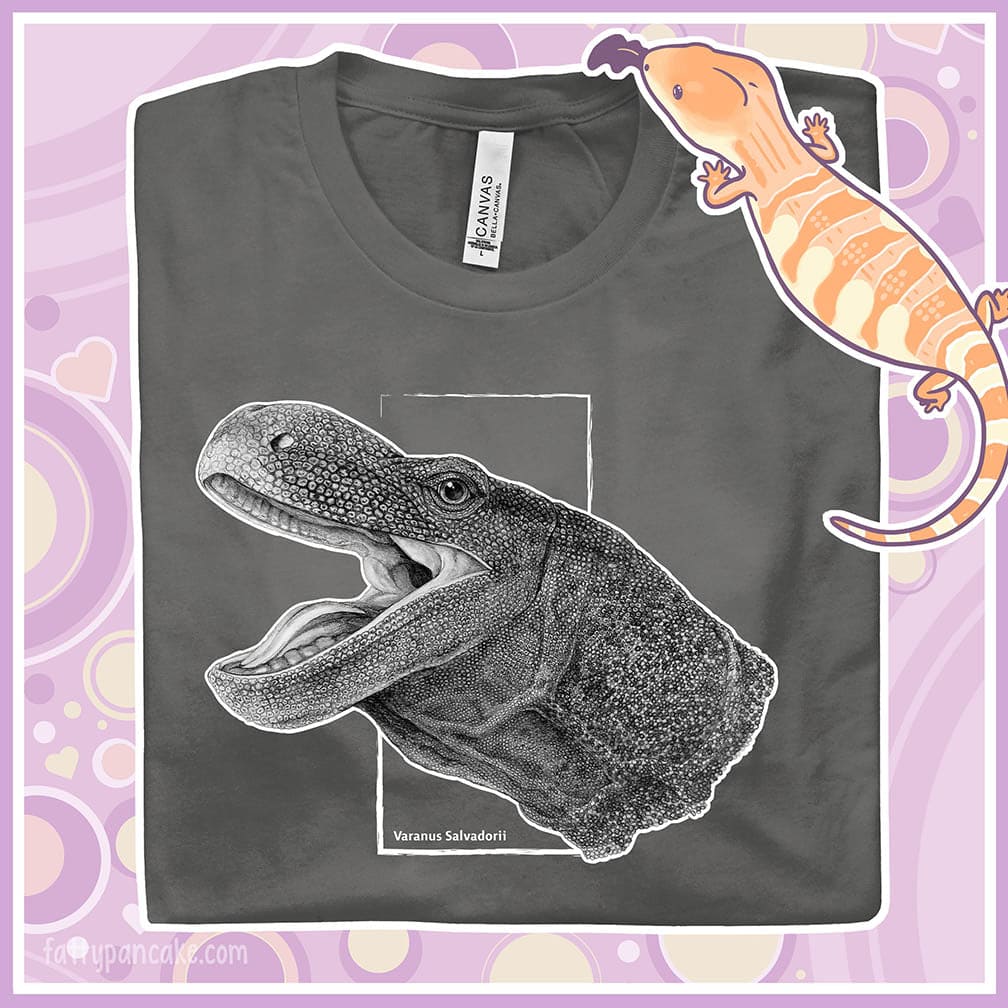 A folded asphalt grey crew neck tee with a black and white detailed drawing of a crocodile monitor head and neck.