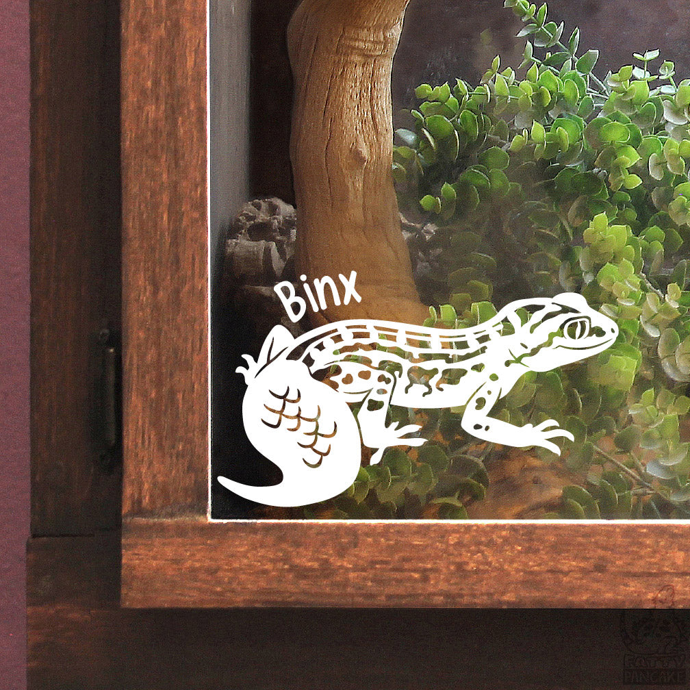 A white vinyl decal of a gecko with the name &