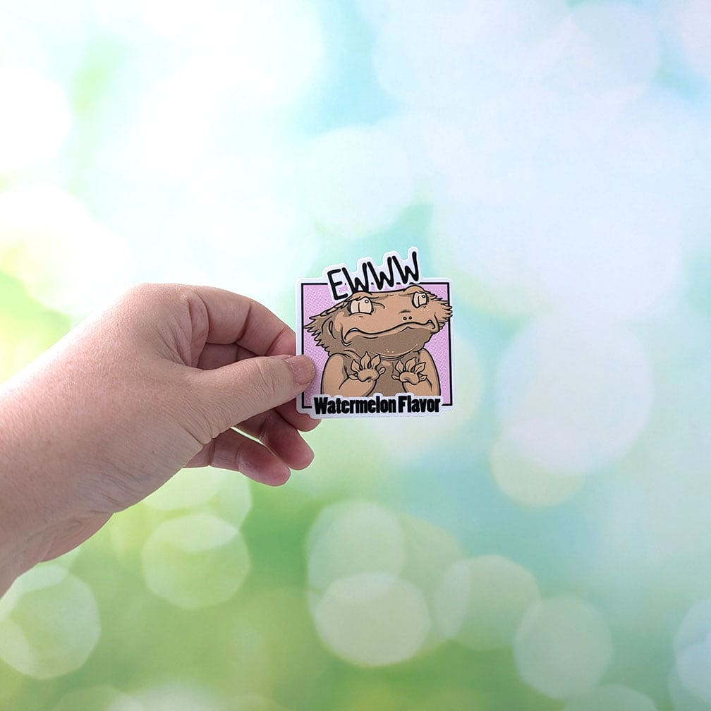 A hand holding the EWW watermelon flavor disgusted crested gecko to show scale. The sticker is 3 inches high and approximately 3 inches wide.