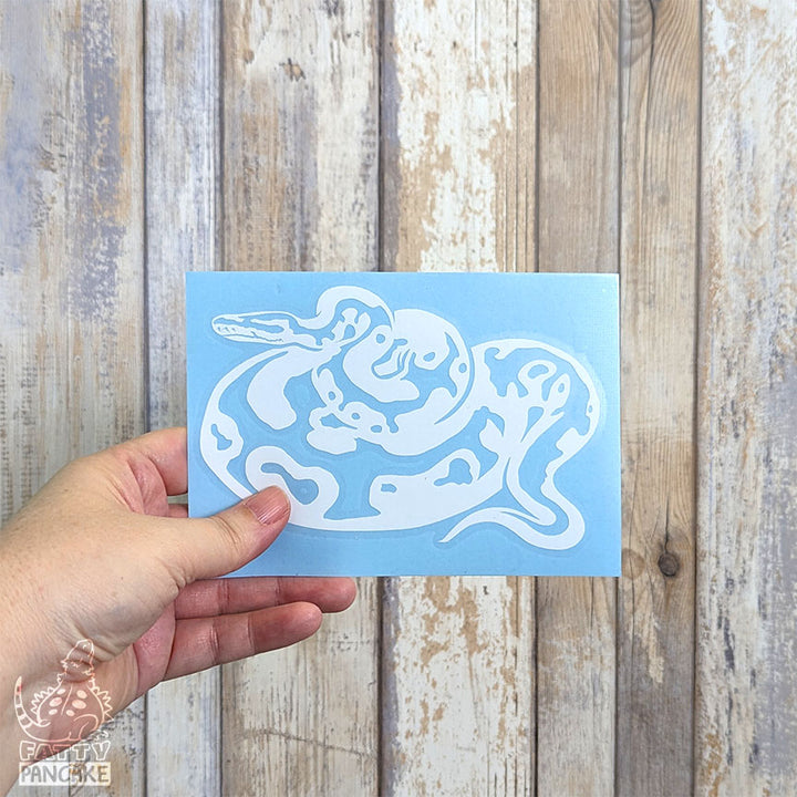 Hand holding final vinyl decal product against a white washed looking wood background.