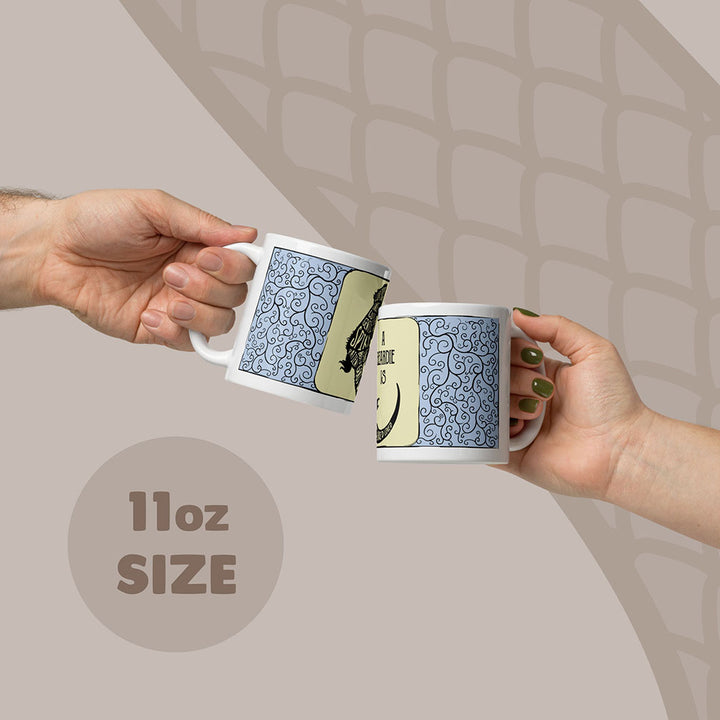 Two white ceramic mugs with an 11oz capacity, each featuring a blue and black swirling filigree pattern on the sides. The mugs display a graphic of a bearded dragon with text in the body.