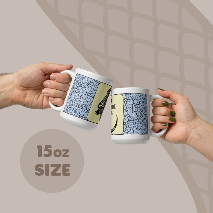 Two white ceramic mugs with an 15oz capacity, each featuring a blue and black swirling filigree pattern on the sides. The mugs display a graphic of a bearded dragon with text in the body.