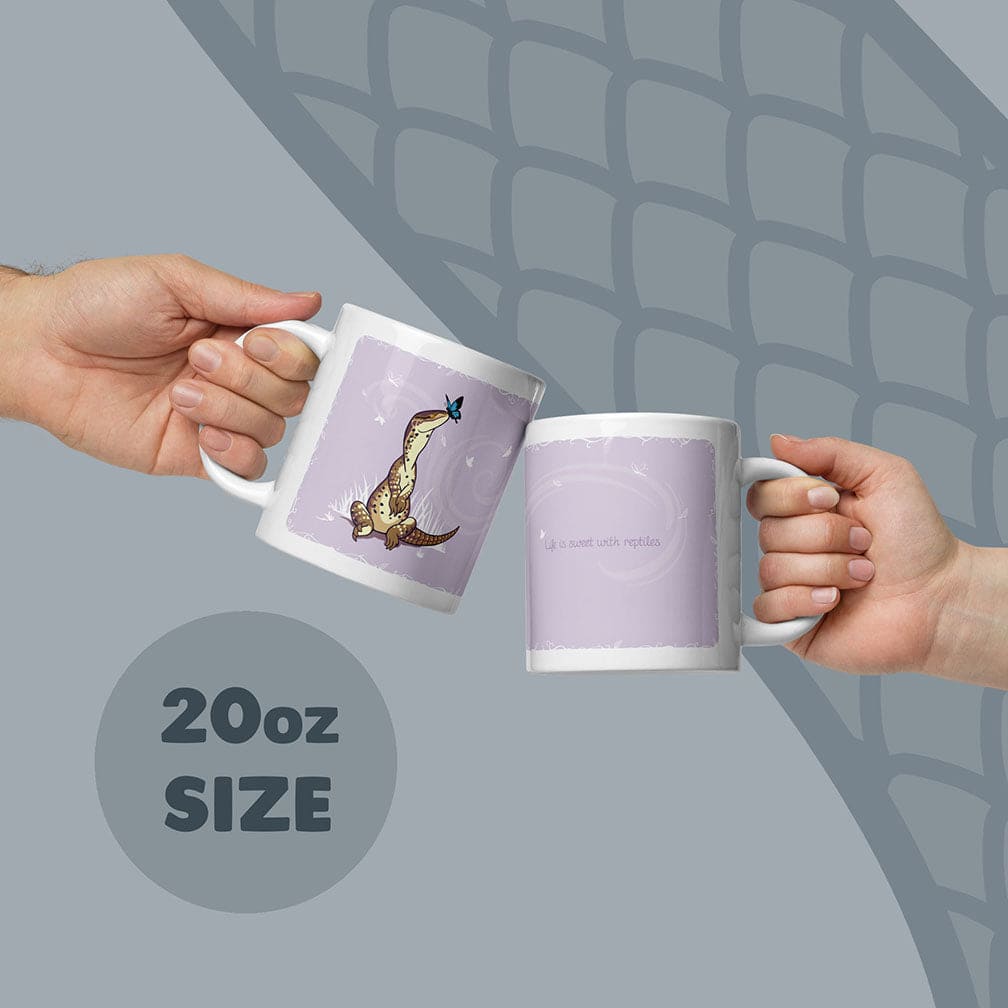 Two white 20oz ceramic mugs with a light purple background. One mug features a brown lizard with a blue butterfly on its nose. The other mug displays the text &