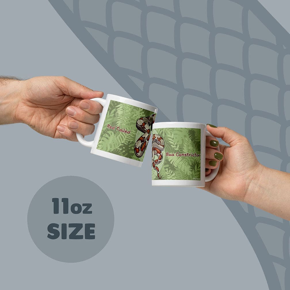 Two white ceramic mugs with an 11oz size capacity, each featuring a green fern leaf pattern and a red-tailed boa constrictor illustration. The text Red Tailed is printed on one mug and Boa Constrictor is printed on the other mug.