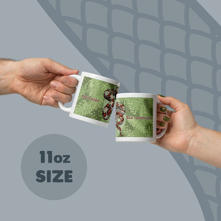 Two white ceramic mugs with an 11oz size capacity, each featuring a green fern leaf pattern and a red-tailed boa constrictor illustration. The text Red Tailed is printed on one mug and Boa Constrictor is printed on the other mug.