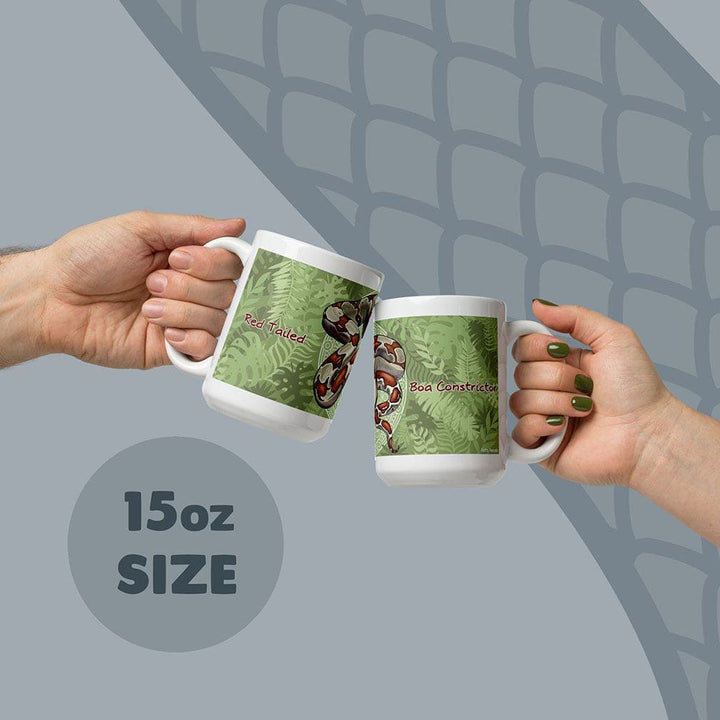 Two white ceramic mugs with an 15oz size capacity, each featuring a green fern leaf pattern and a red-tailed boa constrictor illustration. The text Red Tailed is printed on one mug and Boa Constrictor is printed on the other mug.