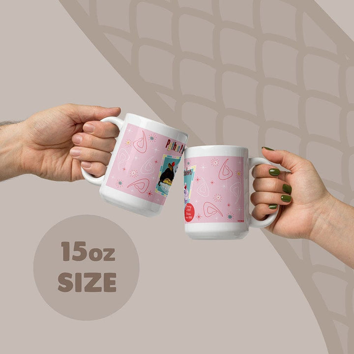 Two white ceramic mugs with a pink design being held by two hands, with an 15oz capacity label on the bottom of the image.