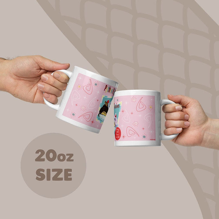 Two white ceramic mugs with a pink design being held by two hands, with an 20oz capacity label on the bottom of the image.