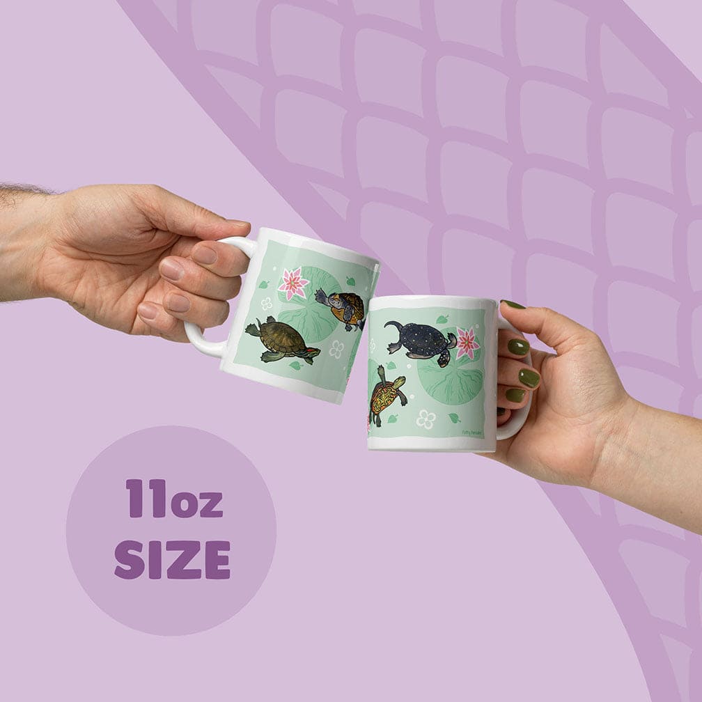 Two white ceramic mugs with an 11oz size capacity, each featuring a light green background decorated with illustrations of fresh water turtles and pink water lilies. The mugs are held up, showcasing the detailed aquatic animal artwork.