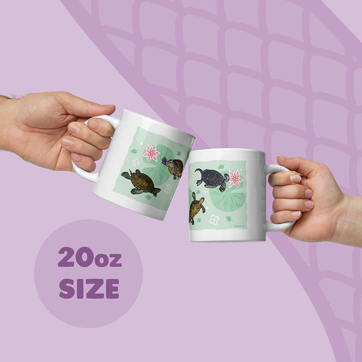 Two white ceramic mugs with an 20oz size capacity, each featuring a light green background decorated with illustrations of fresh water turtles and pink water lilies. The mugs are held up, showcasing the detailed aquatic animal artwork.