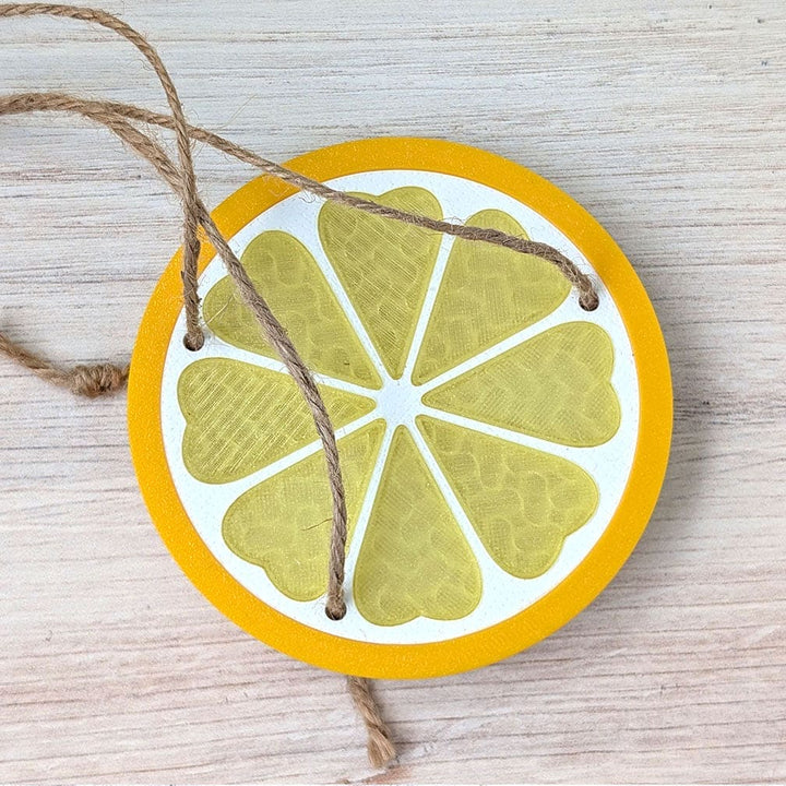 Decorative lemon slice ornament with string on a wooden surface.