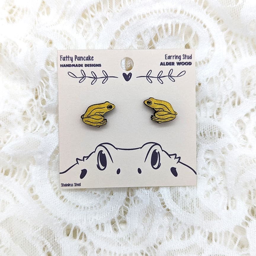 Yellow frog-shaped earrings on a branded card with a white lace background