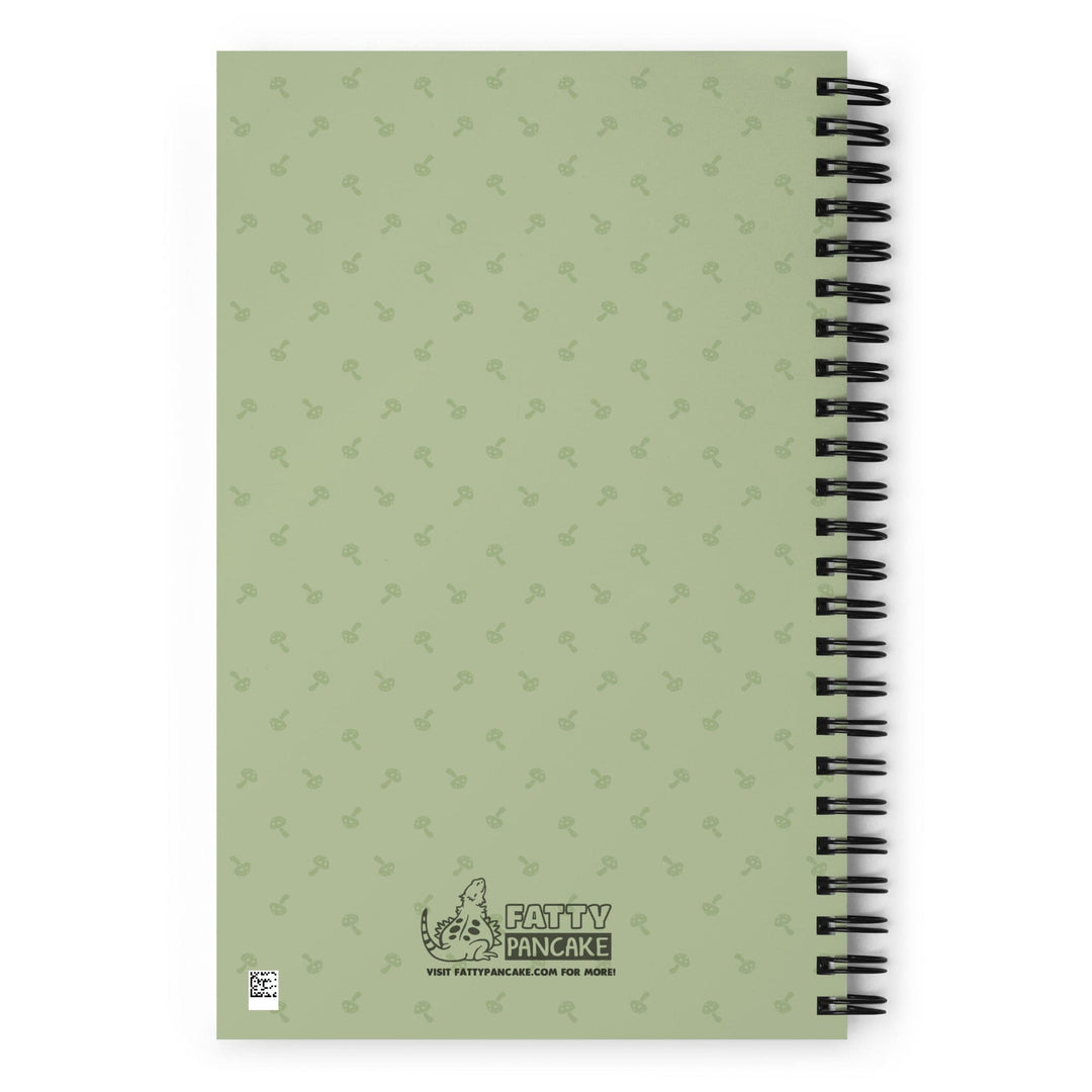 A green journal sitting on a bright white surface. This shows the rear of the journal with a pattern of small mushrooms.