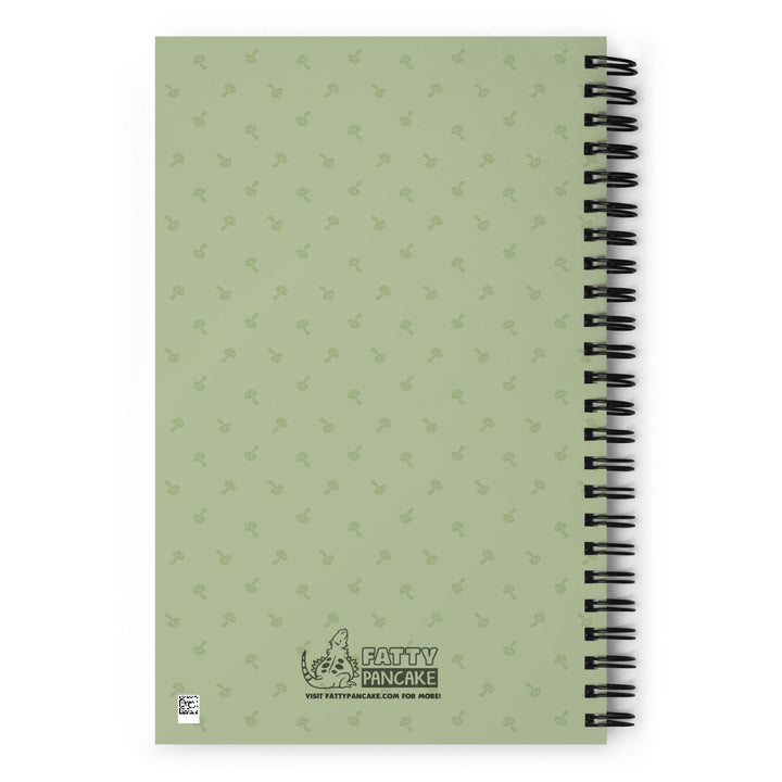 A green journal sitting on a bright white surface. This shows the rear of the journal with a pattern of small mushrooms.