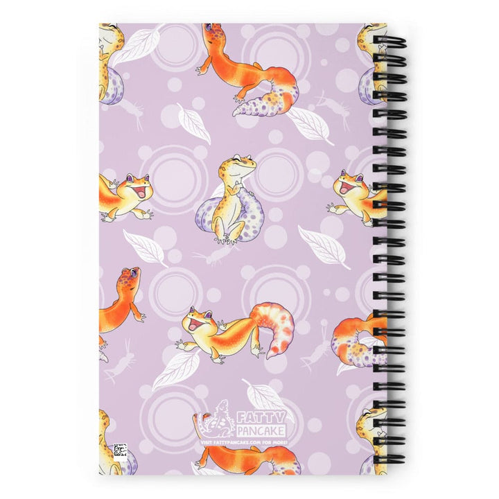A spiral-bound notebook with a lavender cover decorated with a repeating pattern of cartoon leopard geckos in orange, yellow, and white, with a black spiral coil on the right side. There is a logo with the name Fatty Pancake on the center bottom.