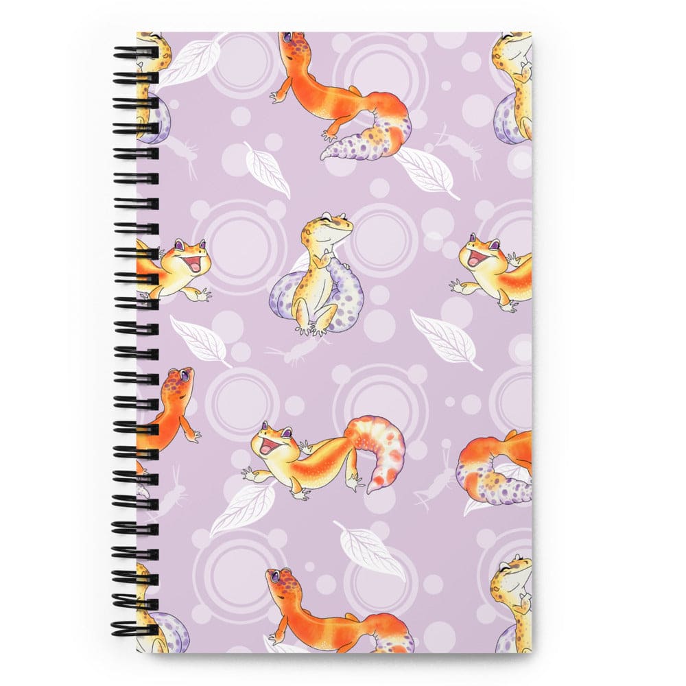 A spiral-bound notebook with a lavender cover decorated with a repeating pattern of orange and yellow leopard geckos, white leaves, and light purple circles, shown on a plain white background.