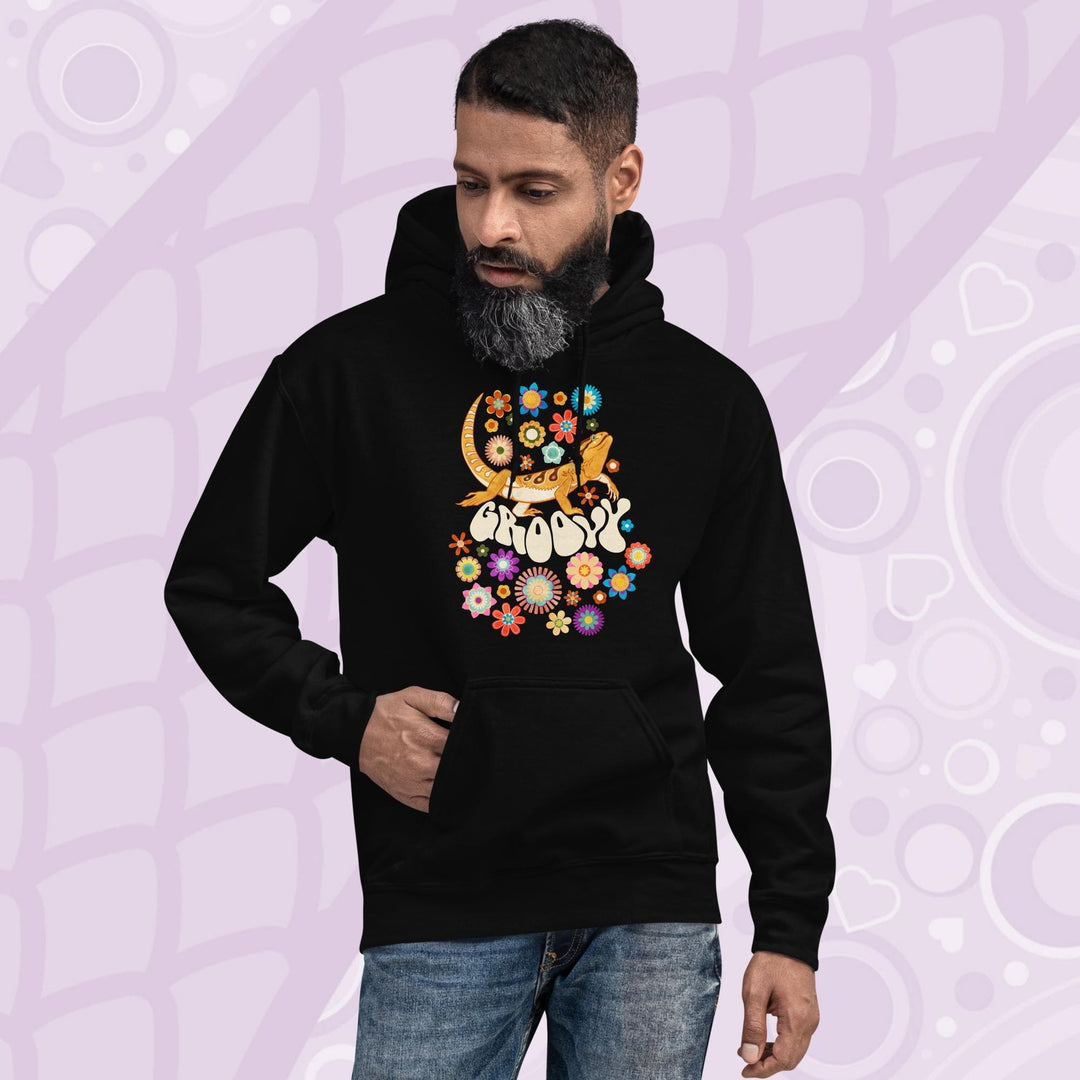 A black hooded sweatshirt with a graphic of a bearded dragon with the word "Groovy" in a retro font surrounded by colorful flowers in a 70's inspired theme.