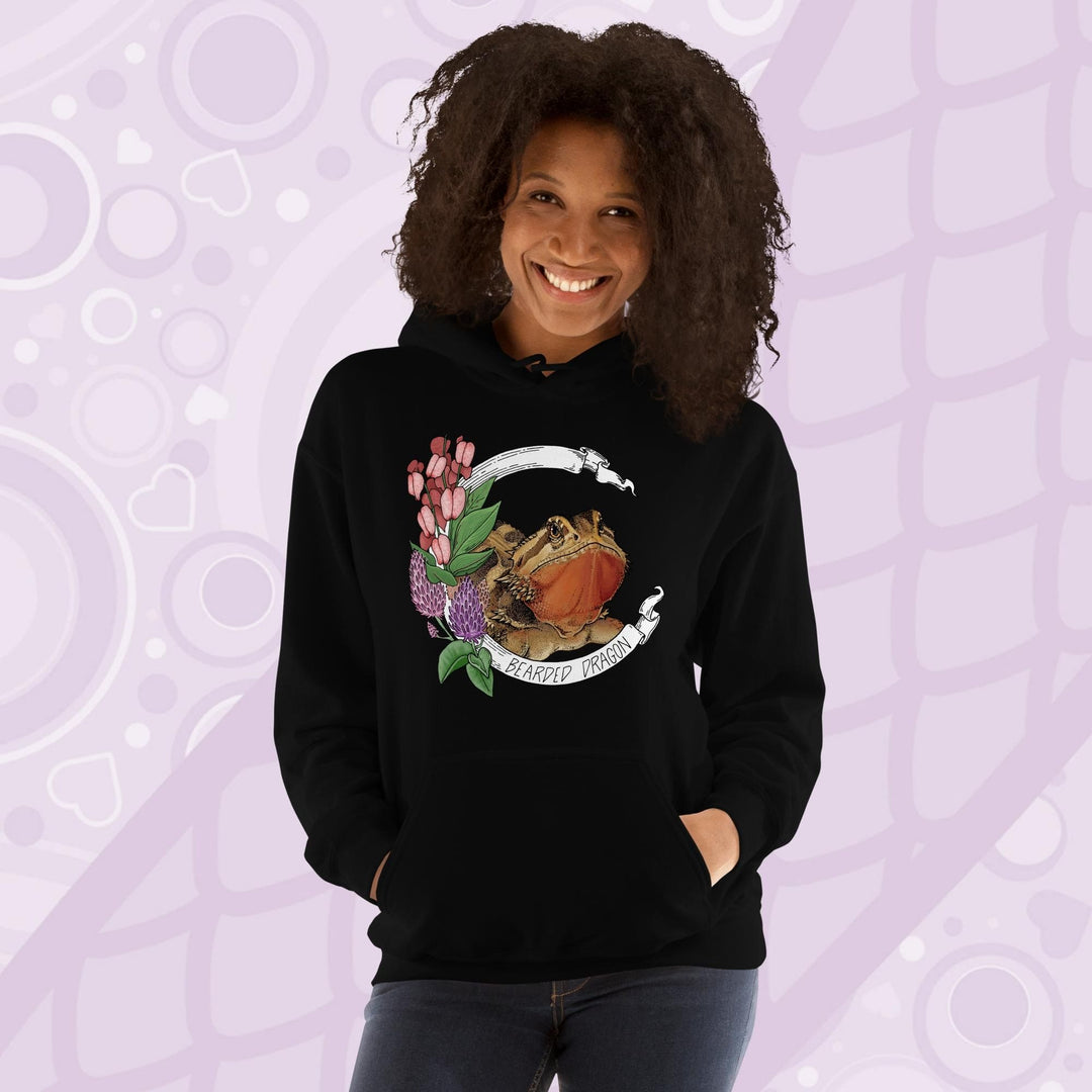 A woman wearing a black hooded sweatshirt with a graphic of a bearded dragon with pink flowers and the text "Bearded Dragon".