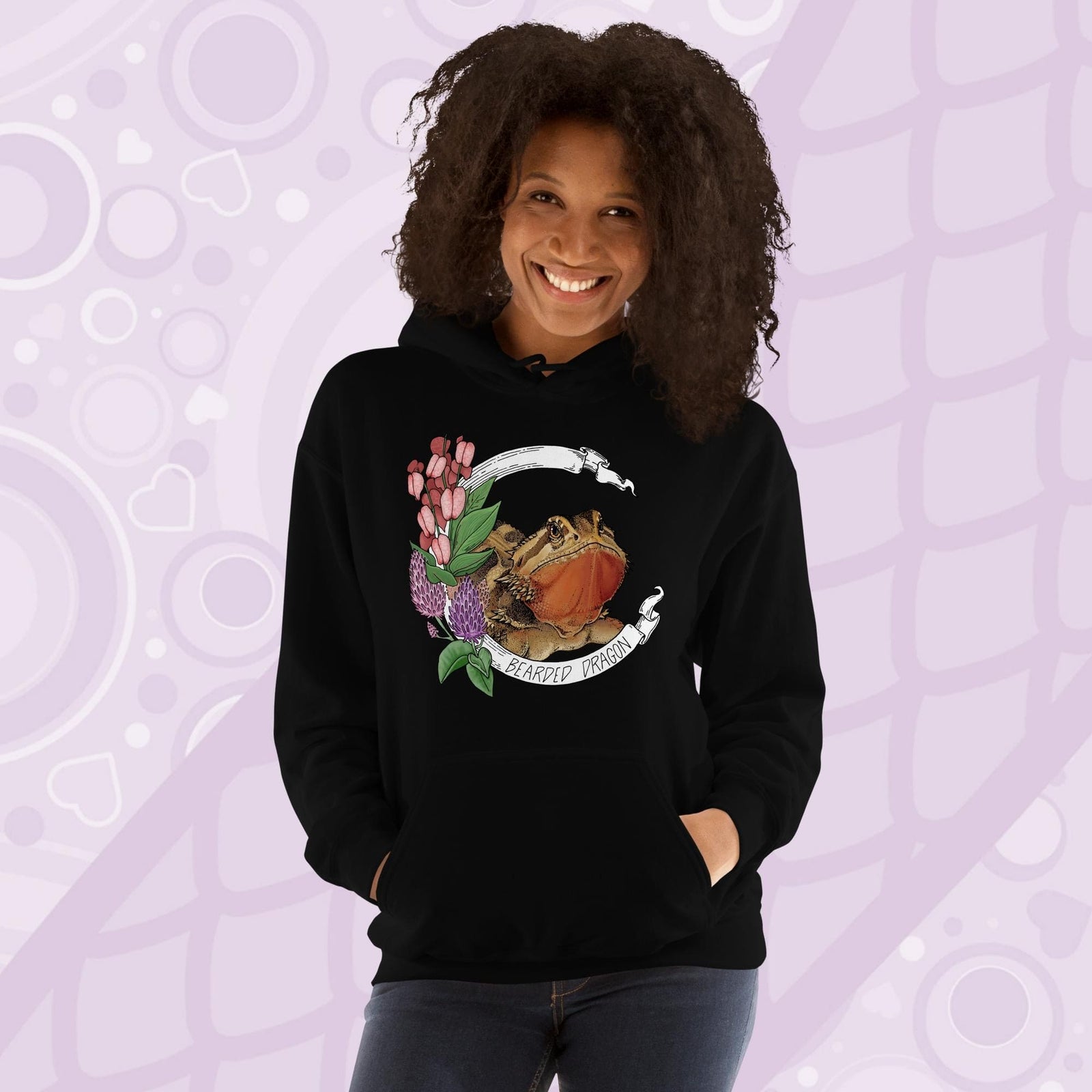 A woman wearing a black hooded sweatshirt with a graphic of a bearded dragon with pink flowers and the text "Bearded Dragon".