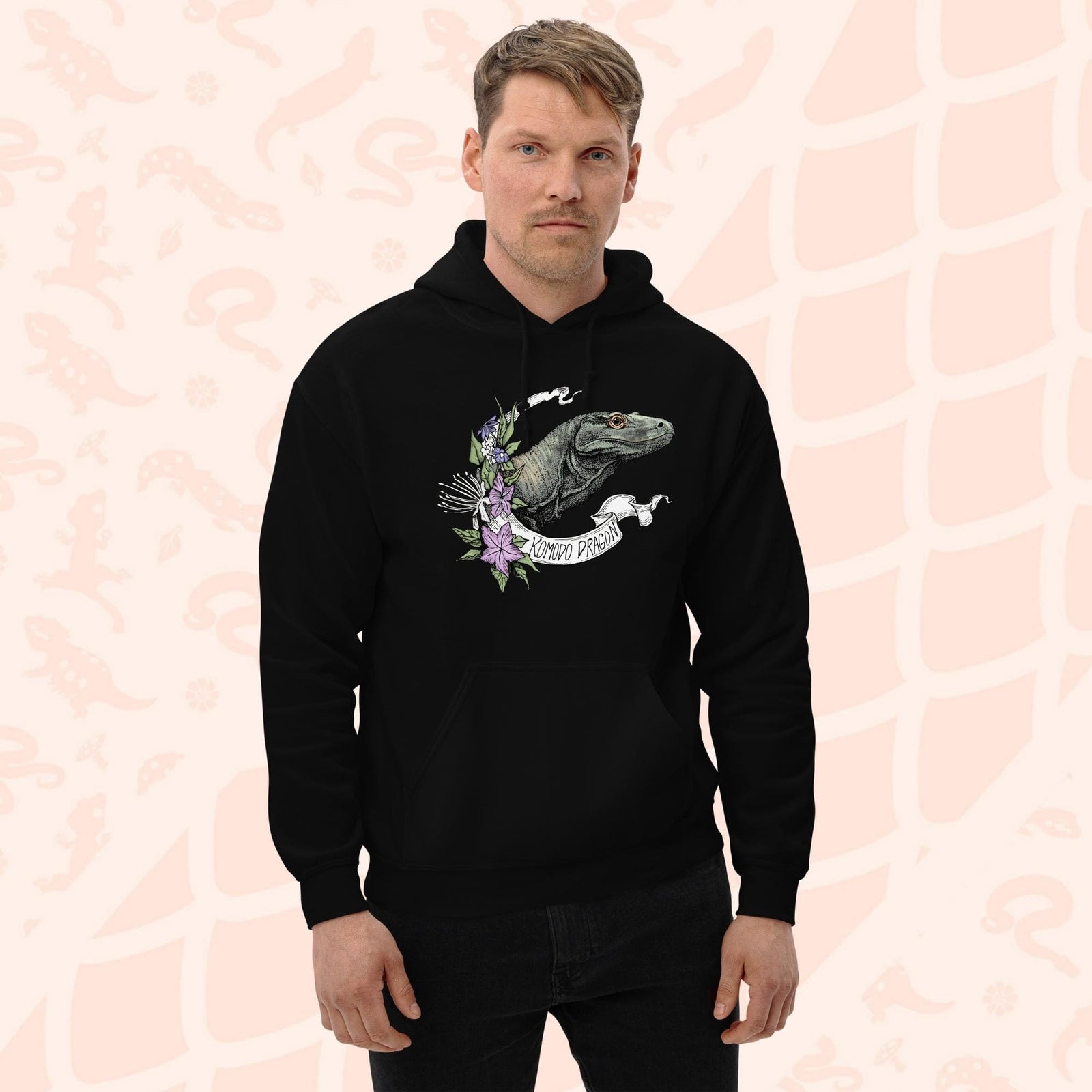 A black hooded sweatshirt with a graphic print of a Komodo dragon with purple flowers and the text "Komodo Dragon" on the white banner framing the design. The hoodie has a front pocket.