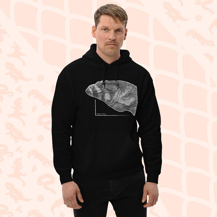 A man wearing a black pullover hoodie with a graphic print of a pencil drawing of a lace monitor lizard. It's a profile view and highly detailed showing a close up of the scales. The hoodie has a front pocket.