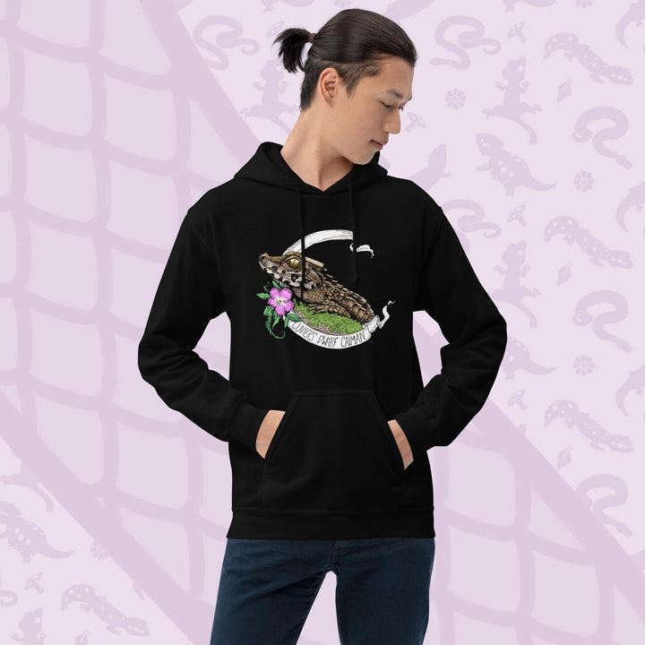 Black hooded sweatshirt featuring a detailed illustration of a caiman with a flower and banner. The banner reads "Cunners Park Caiman". The caiman is brown and green, with a pink flower and green foliage. The sweatshirt has a front pocket and a drawstring hood.