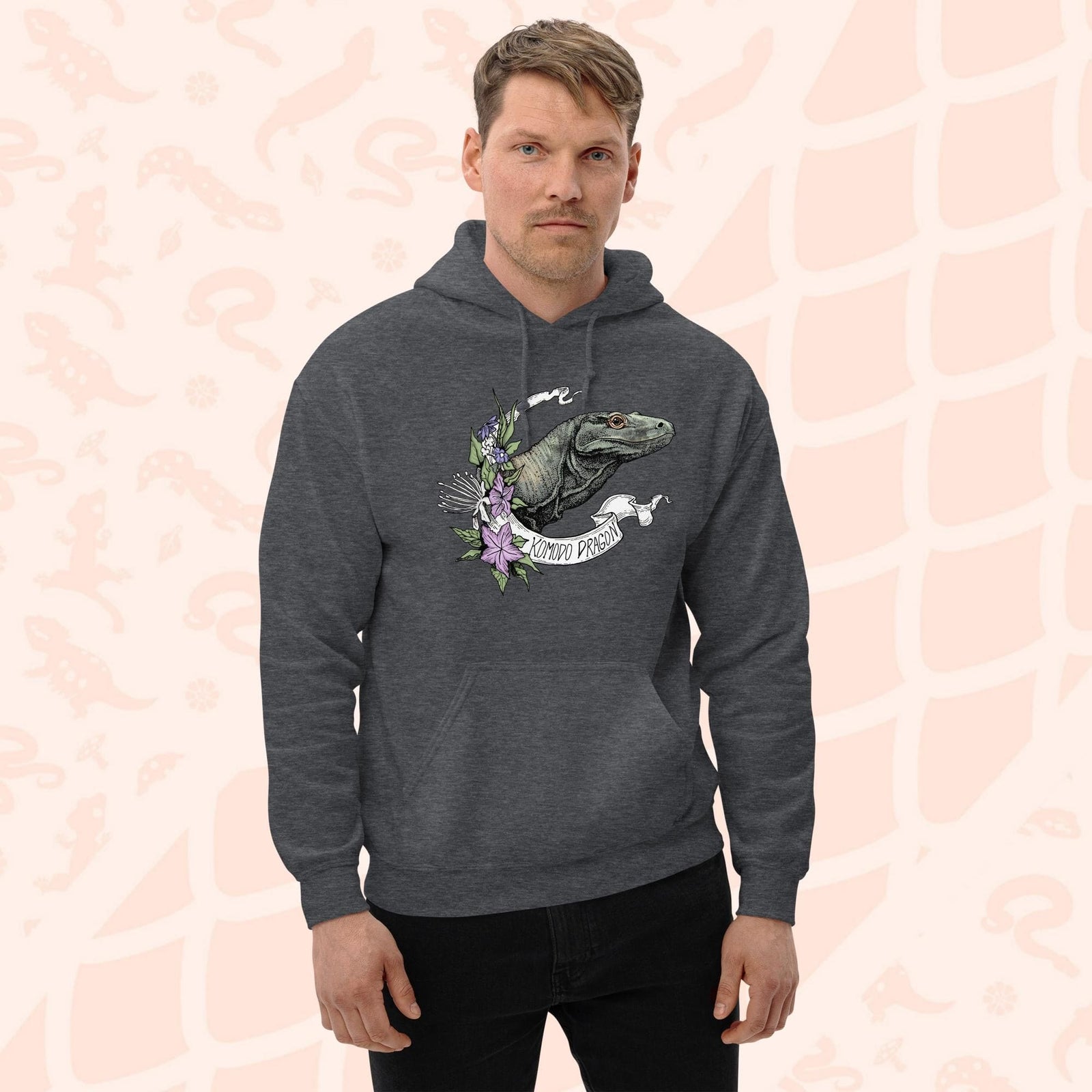 A dark gray hooded sweatshirt with a graphic print of a Komodo dragon with purple flowers and the text "Komodo Dragon" on the white banner framing the design. The hoodie has a front pocket.