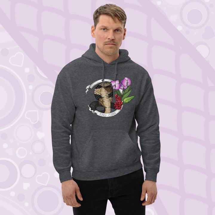 A man wearing a dark gray hooded sweatshirt with a graphic of a king cobra with pink orchids  and smaller red flowers on the right side of the design. The text "KING COBRA" is printed below the snake. The hoodie has a front pocket.