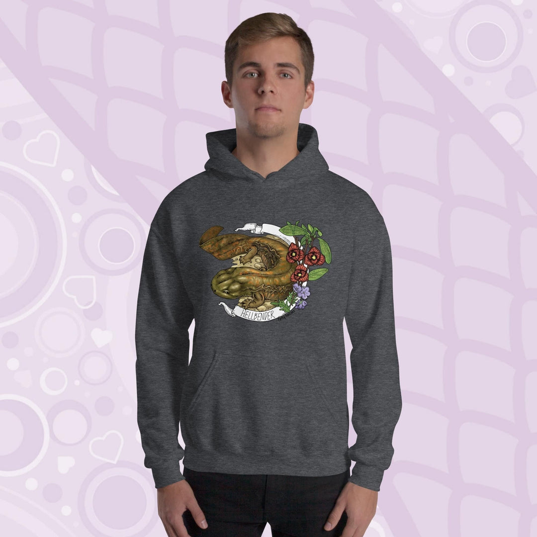 A man wearing a dark gray hoodie featuring a detailed illustration of a salamander with the text "HELLBENDER" in white. The design includes floral elements in red, green, and purple. The hoodie has a front pocket and a hood.