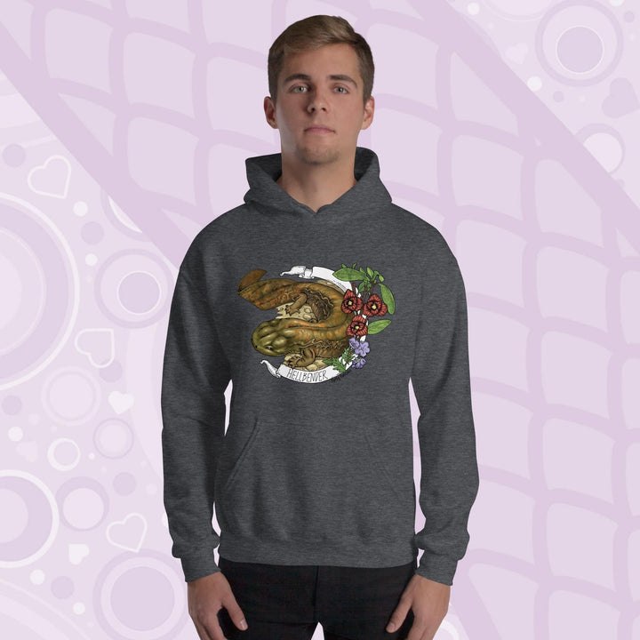 A man wearing a dark gray hoodie featuring a detailed illustration of a salamander with the text "HELLBENDER" in white. The design includes floral elements in red, green, and purple. The hoodie has a front pocket and a hood.
