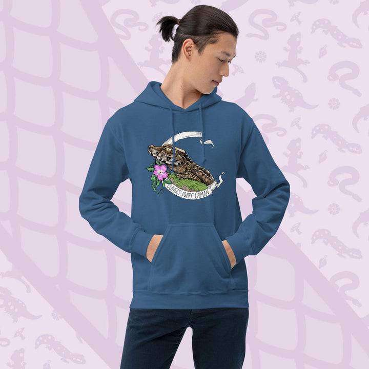 Blue hooded sweatshirt featuring a detailed illustration of a caiman with a flower and banner. The banner reads "Cuviers Dwarf Caiman". The caiman is brown and green, with a pink flower and green foliage. The sweatshirt has a front pocket and a drawstring hood.