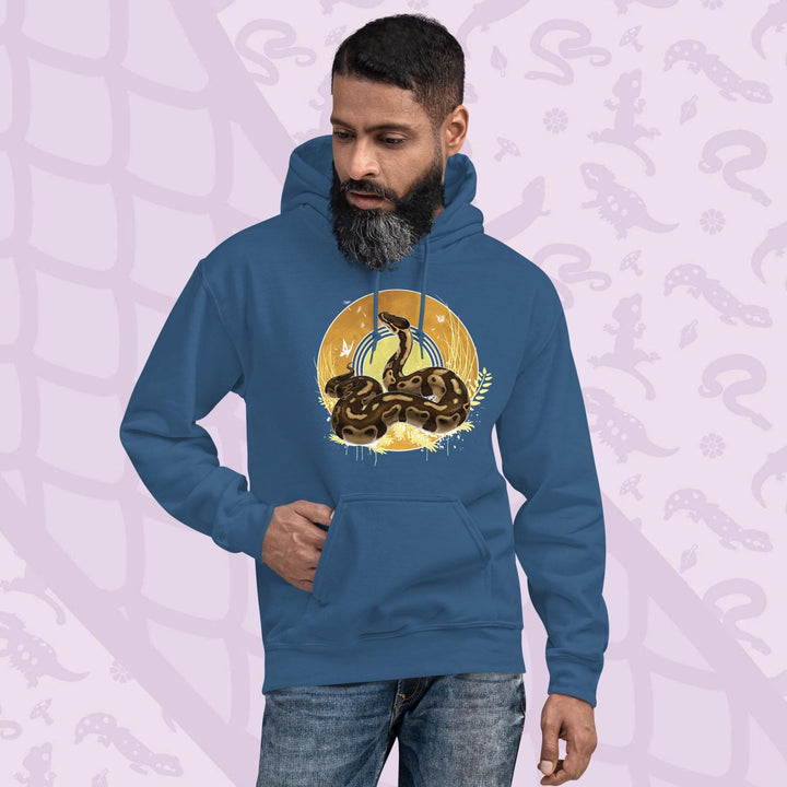 Neutral blue hoodie with a graphic of a normal ball python snake with it's amber and brown colored scales coiled in a circle with it's head lifted up and looking upward. Behind it is a series of circles with golden hues and tall amber grasses with white butterflies and seeds floating on the wind. The hoodie has a front pocket.