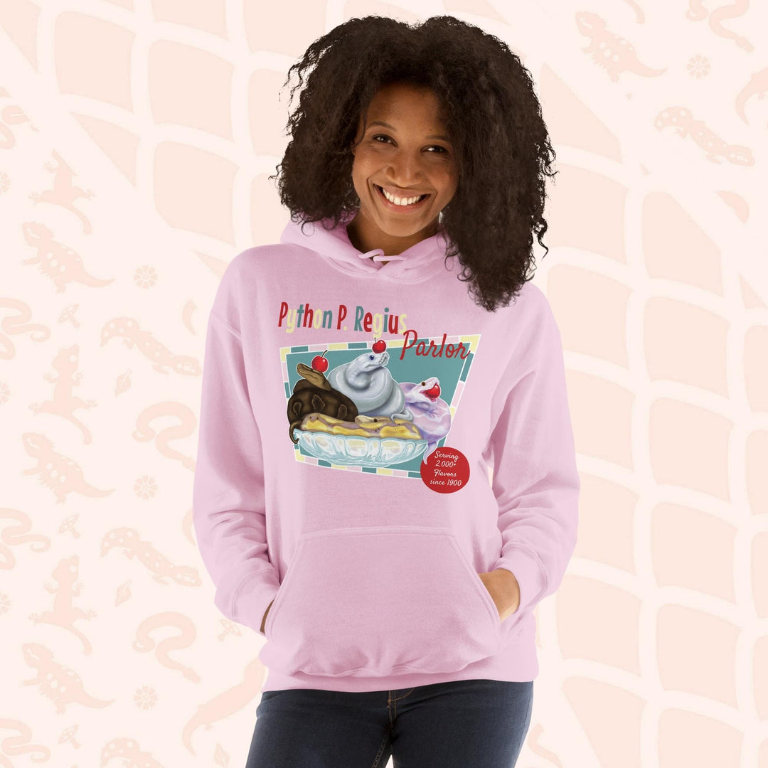 A soft pink hoodie with a retro-style graphic of a sundae with three ball pythons on top. The graphic says "Python P. Regius Parlor" and "Serving 2,000+ flavors since 1990".