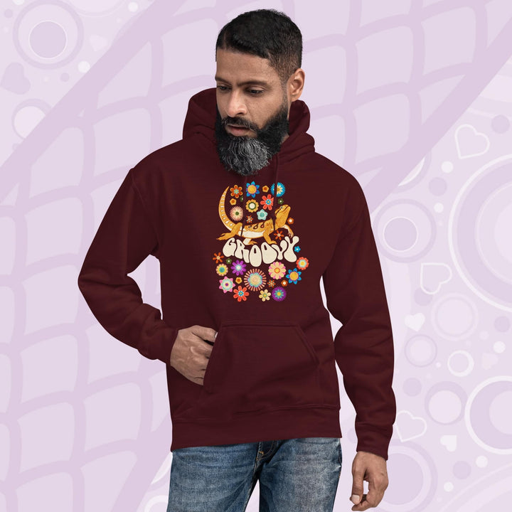 A dark red maroon hooded sweatshirt with a graphic of a bearded dragon with the word "Groovy" in a retro font surrounded by colorful flowers in a 70's inspired theme.