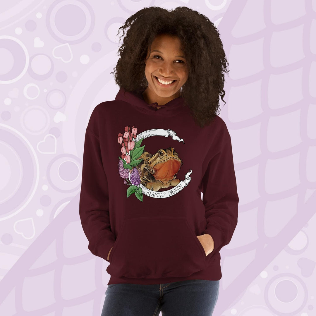 A woman wearing a dark red maroon colored hooded sweatshirt with a graphic of a bearded dragon with pink flowers and the text "Bearded Dragon".