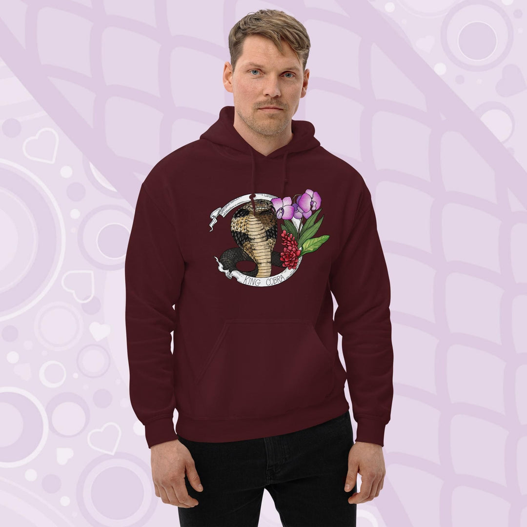 A man wearing a dark maroon red hooded sweatshirt with a graphic of a king cobra with pink orchids  and smaller red flowers on the right side of the design. The text "KING COBRA" is printed below the snake. The hoodie has a front pocket.