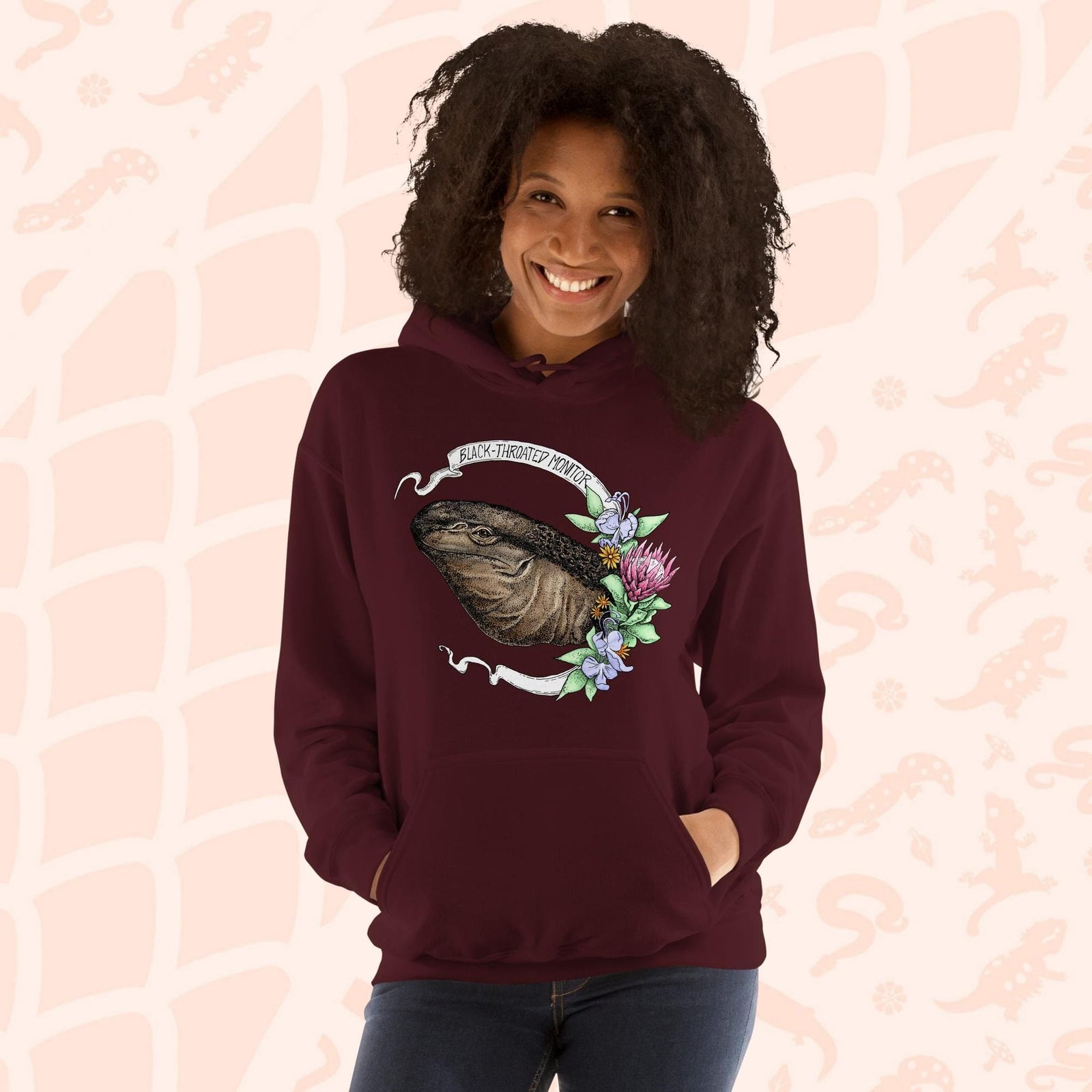 A dark red maroon hooded sweatshirt with a graphic of a black-throated monitor lizard with flowers and the text "Black-throated Monitor" on a white banner.
