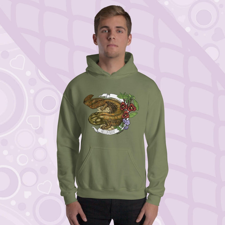 A man wearing a olive green hoodie featuring a detailed illustration of a salamander with the text "HELLBENDER" in white. The design includes floral elements in red, green, and purple. The hoodie has a front pocket and a hood.
