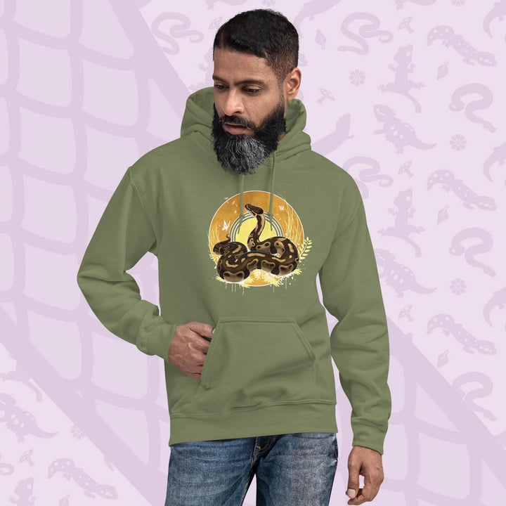 Olive Green hoodie with a graphic of a normal ball python snake with it's amber and brown colored scales coiled in a circle with it's head lifted up and looking upward. Behind it is a series of circles with golden hues and tall amber grasses with white butterflies and seeds floating on the wind. The hoodie has a front pocket.